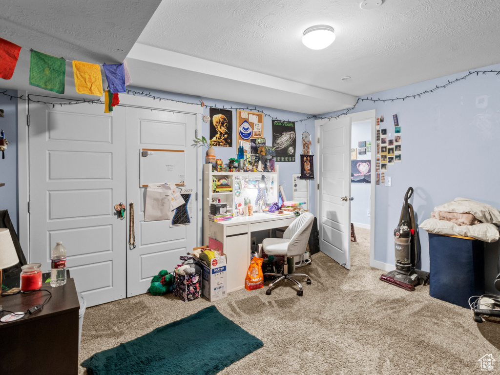 Carpeted home office featuring a textured ceiling