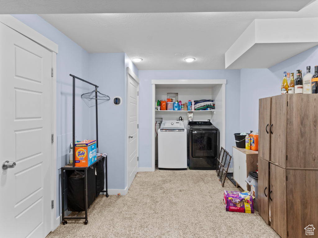 Clothes washing area with washer and clothes dryer, carpet flooring, and baseboards