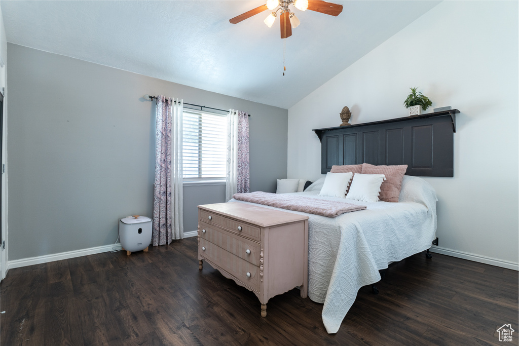 Bedroom featuring dark wood-style floors, vaulted ceiling, baseboards, and a ceiling fan