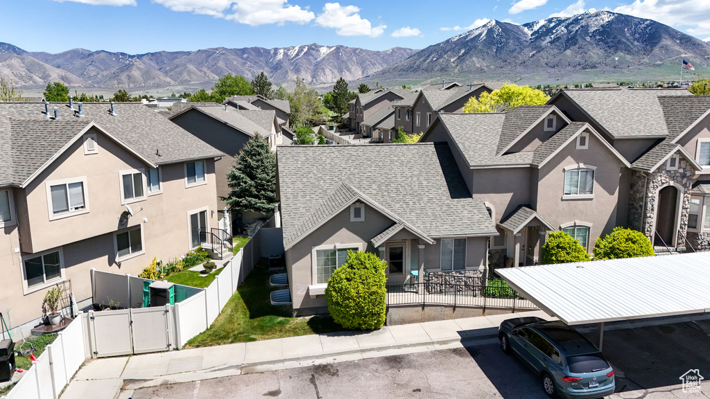 View of front facade featuring stucco siding, a mountain view, fence, roof with shingles, and a gate