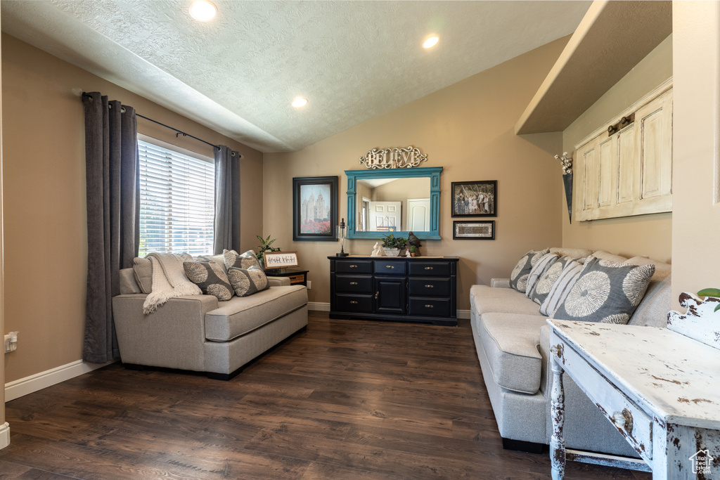 Living area featuring vaulted ceiling, recessed lighting, dark wood-type flooring, baseboards, and a textured ceiling