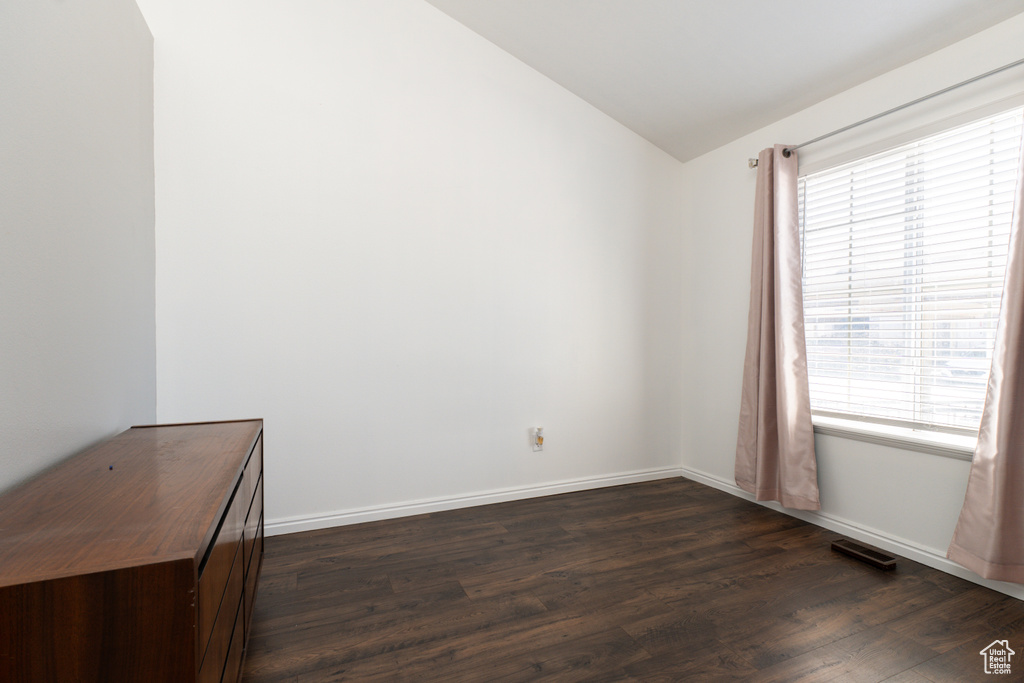 Empty room with lofted ceiling, plenty of natural light, dark wood-style flooring, and baseboards