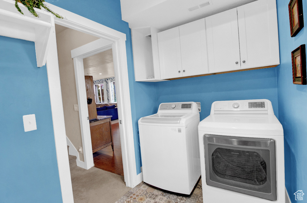 Laundry room featuring cabinet space, washing machine and clothes dryer, light colored carpet, and baseboards