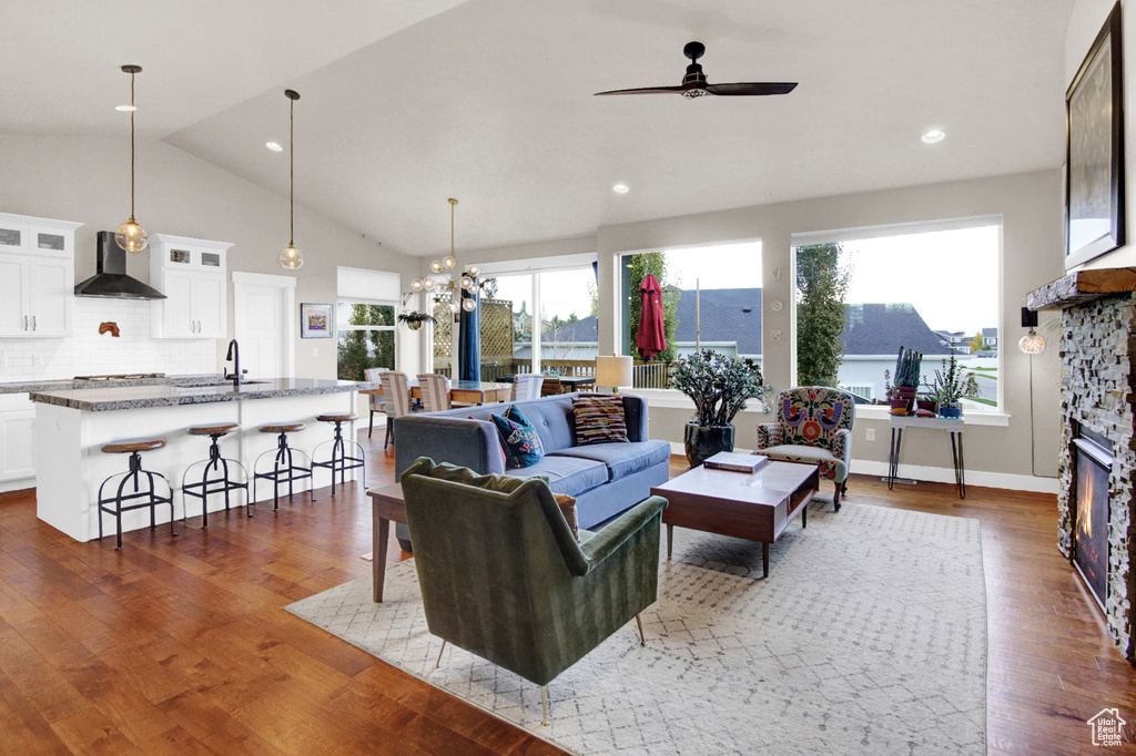 Living room featuring ceiling fan, vaulted ceiling, wood finished floors, a chandelier, and recessed lighting