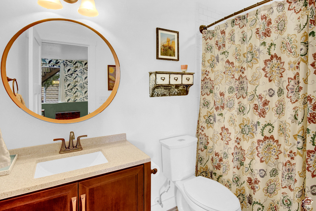 Full bathroom with toilet, vanity, and curtained shower