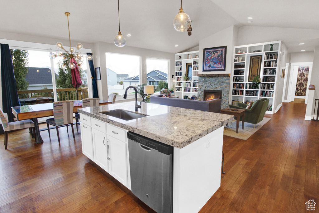 Kitchen with a sink, stainless steel dishwasher, vaulted ceiling, a fireplace, and pendant lighting