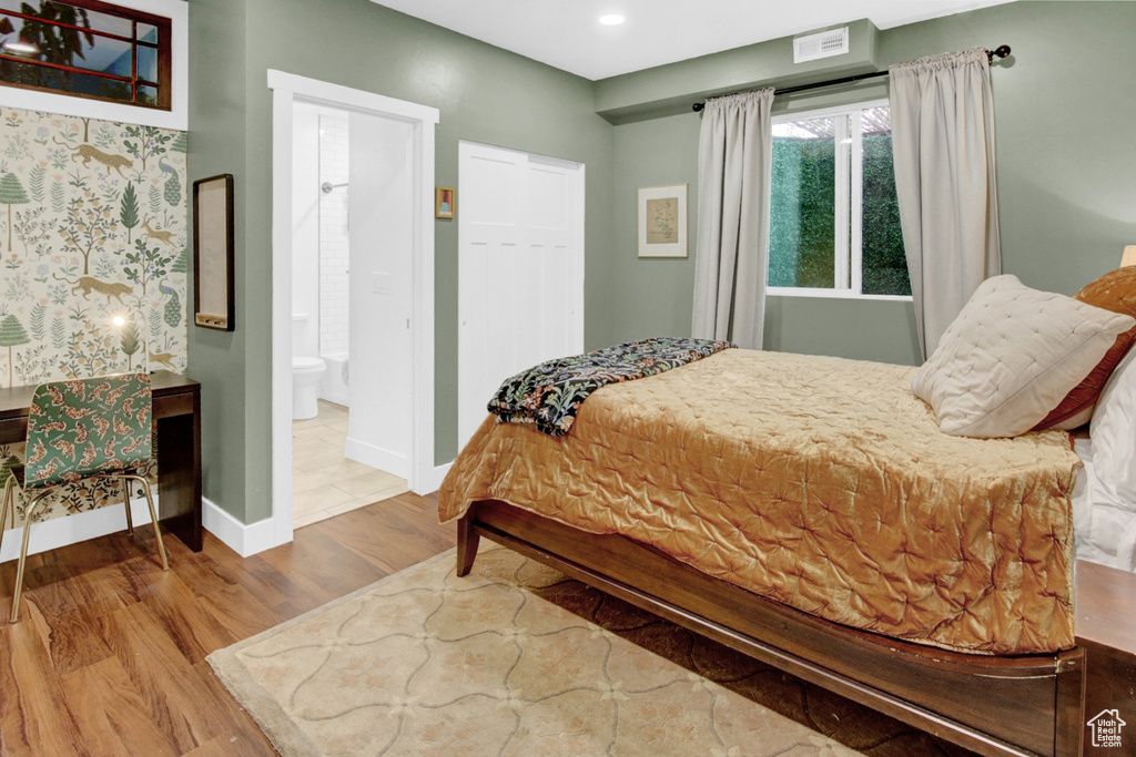 Bedroom featuring wood finished floors, baseboards, recessed lighting, and ensuite bath