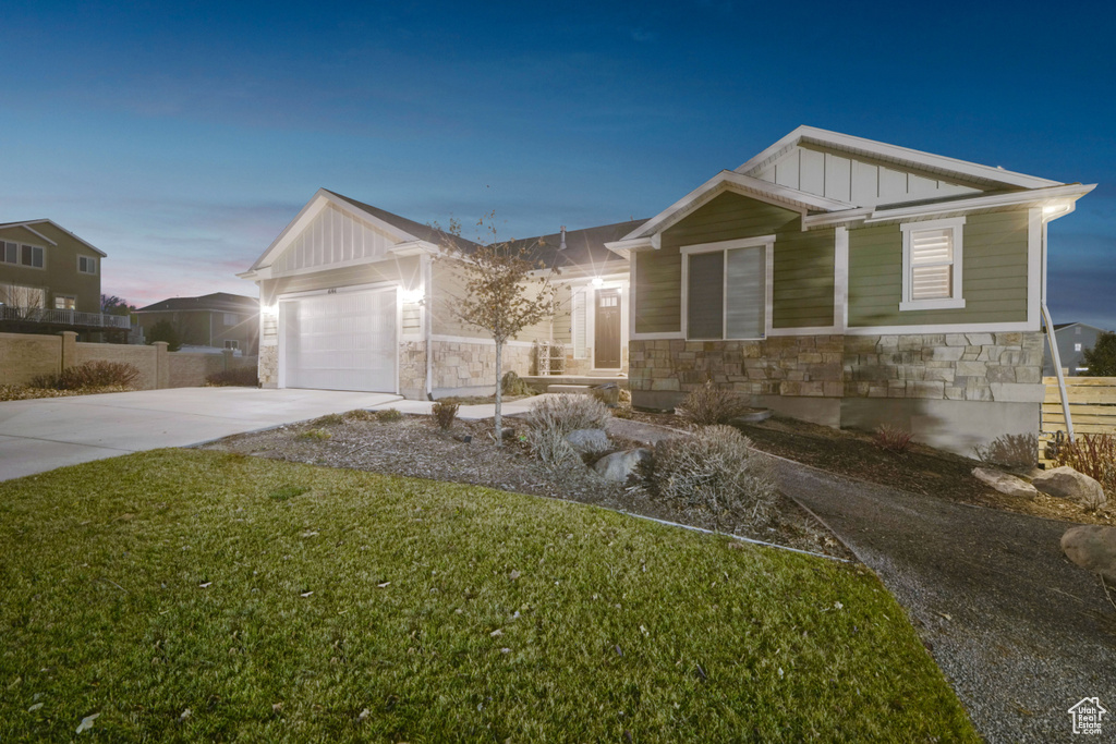 View of front of home featuring board and batten siding, stone siding, driveway, and a garage