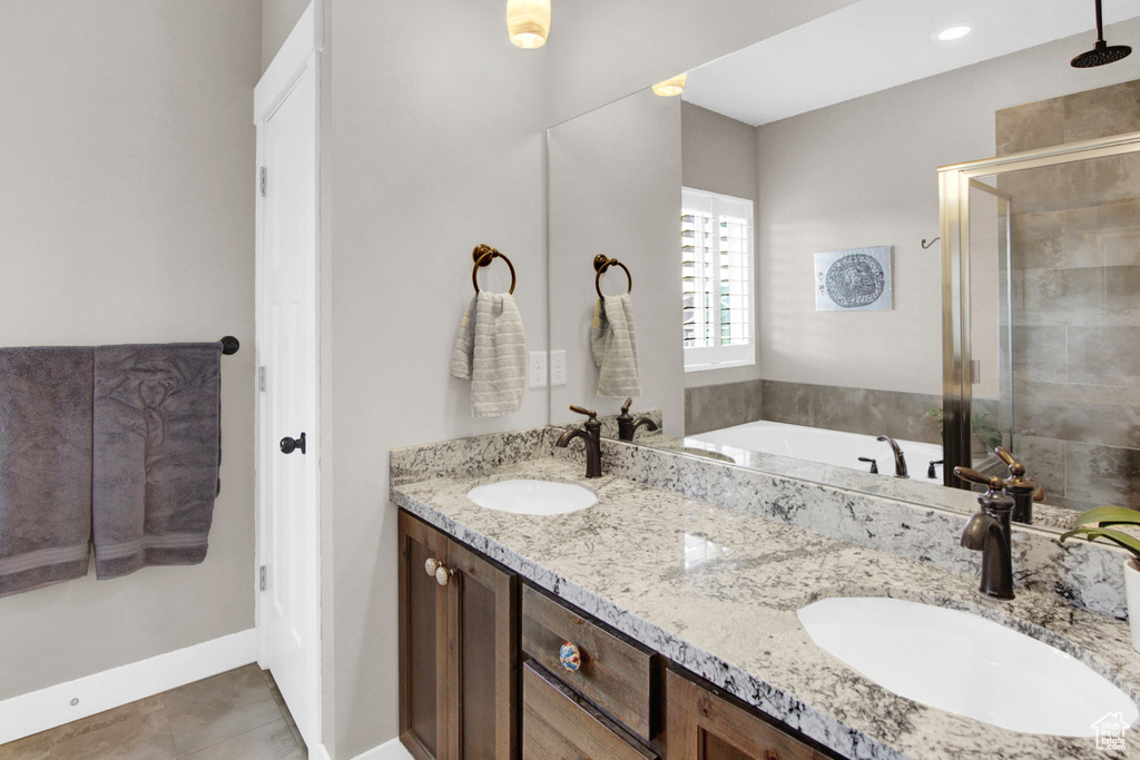 Bathroom featuring a shower stall, double vanity, tile patterned floors, and a garden tub
