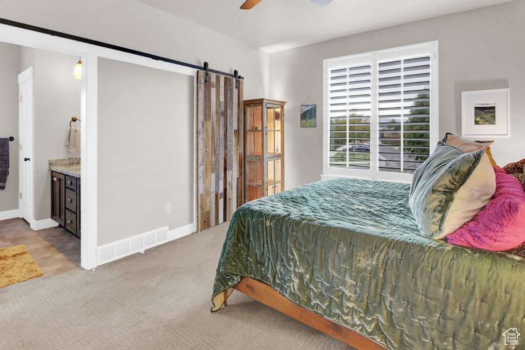 Carpeted bedroom featuring a barn door, ceiling fan, and baseboards