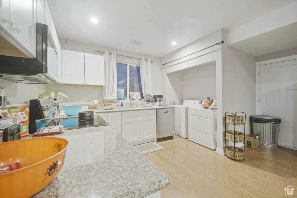 Kitchen featuring stainless steel dishwasher, light wood-type flooring, a sink, white cabinets, and recessed lighting
