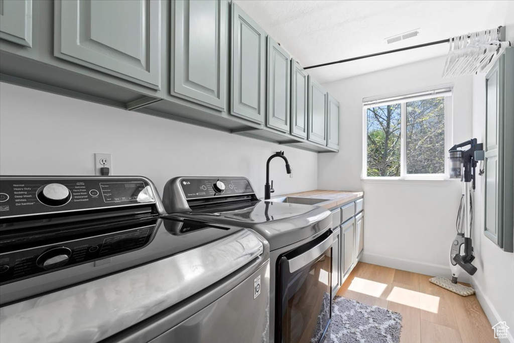 Laundry room featuring cabinet space, independent washer and dryer, light wood finished floors, and baseboards