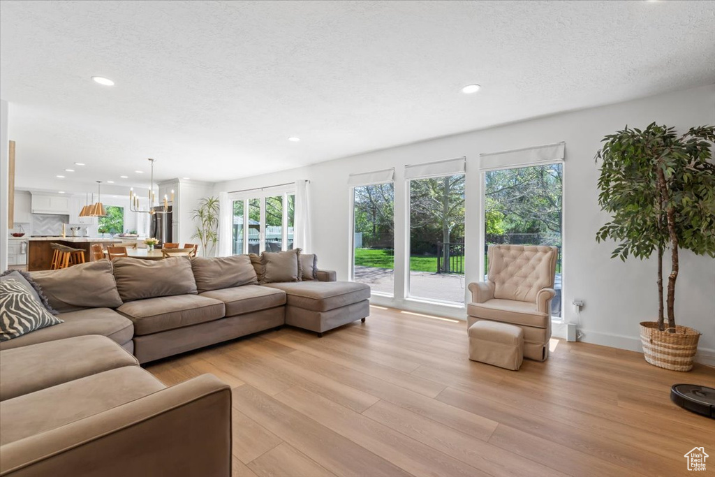 Living area with light wood finished floors, recessed lighting, a chandelier, baseboards, and a textured ceiling