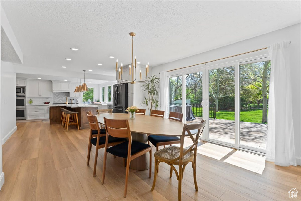 Dining room featuring plenty of natural light, light wood-style floors, recessed lighting, a textured ceiling, and a chandelier