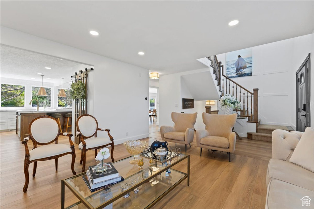 Living room with stairway, light wood-style flooring, recessed lighting, and baseboards