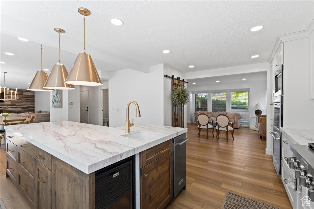 Kitchen with open floor plan, beverage cooler, a sink, wood finished floors, and a barn door