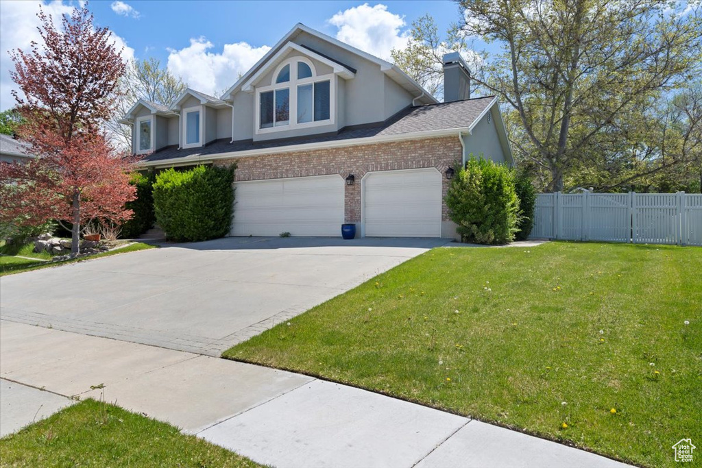 View of front of house with brick siding, stucco siding, a chimney, concrete driveway, and an attached garage