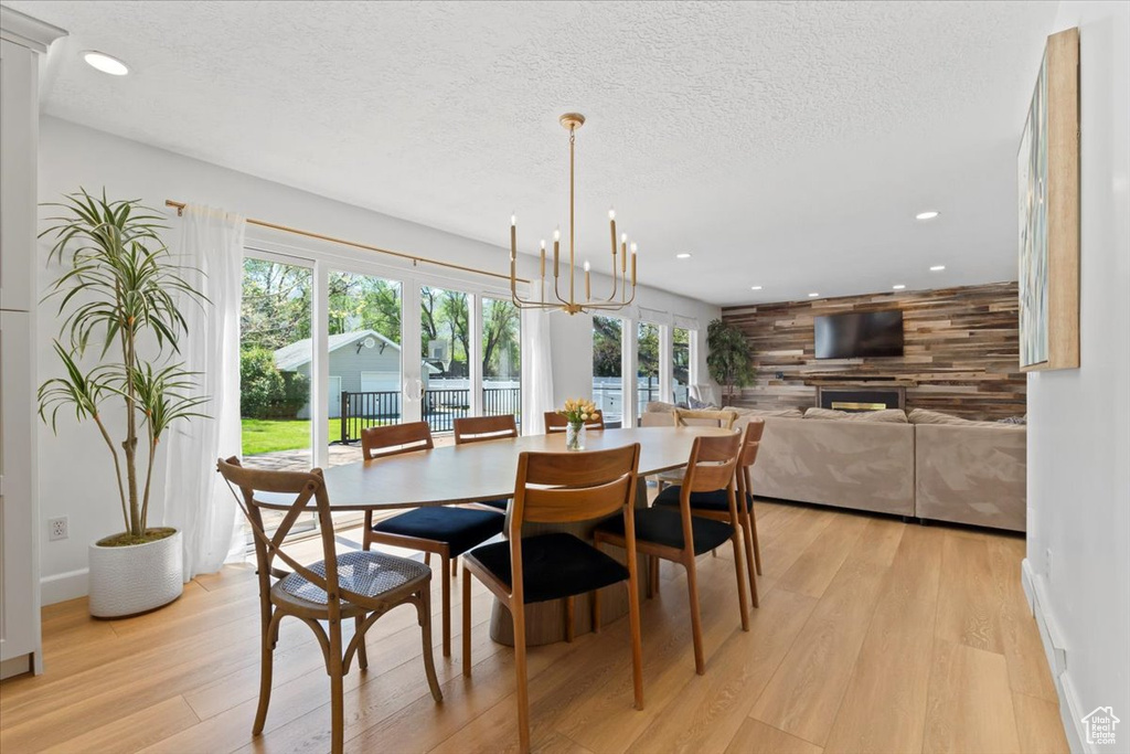 Dining room with light wood-type flooring, recessed lighting, a textured ceiling, a chandelier, and baseboards