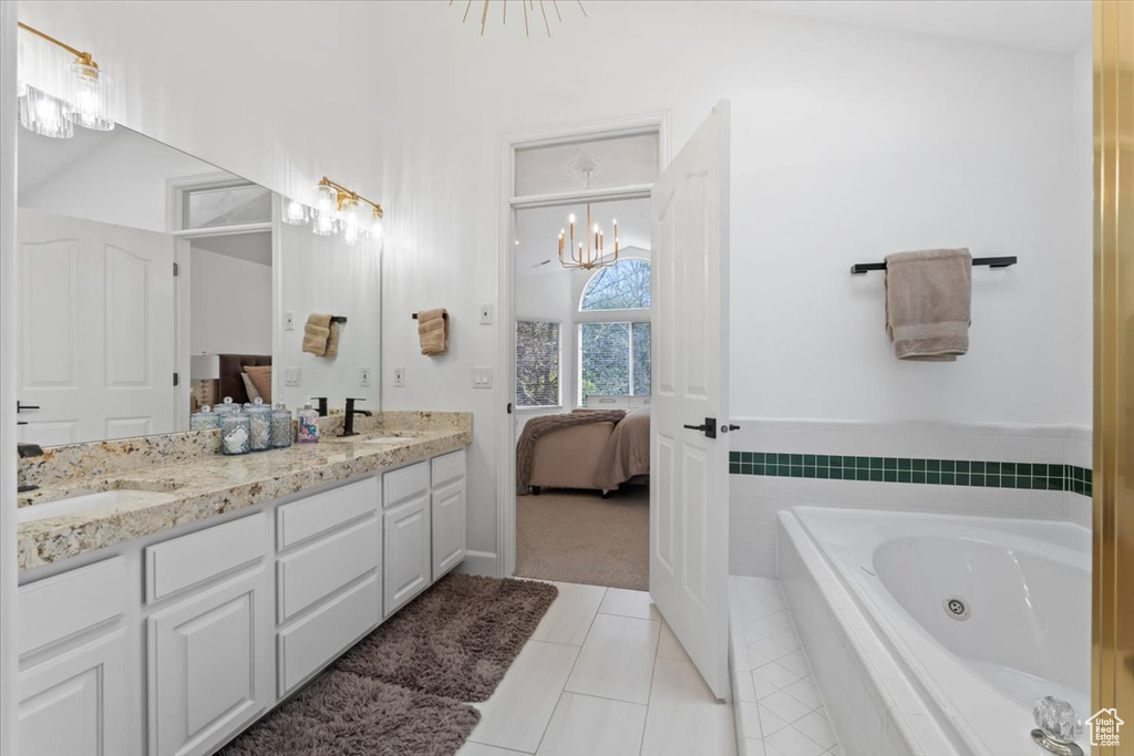Ensuite bathroom featuring double vanity, tile patterned flooring, a tub with jets, and a chandelier
