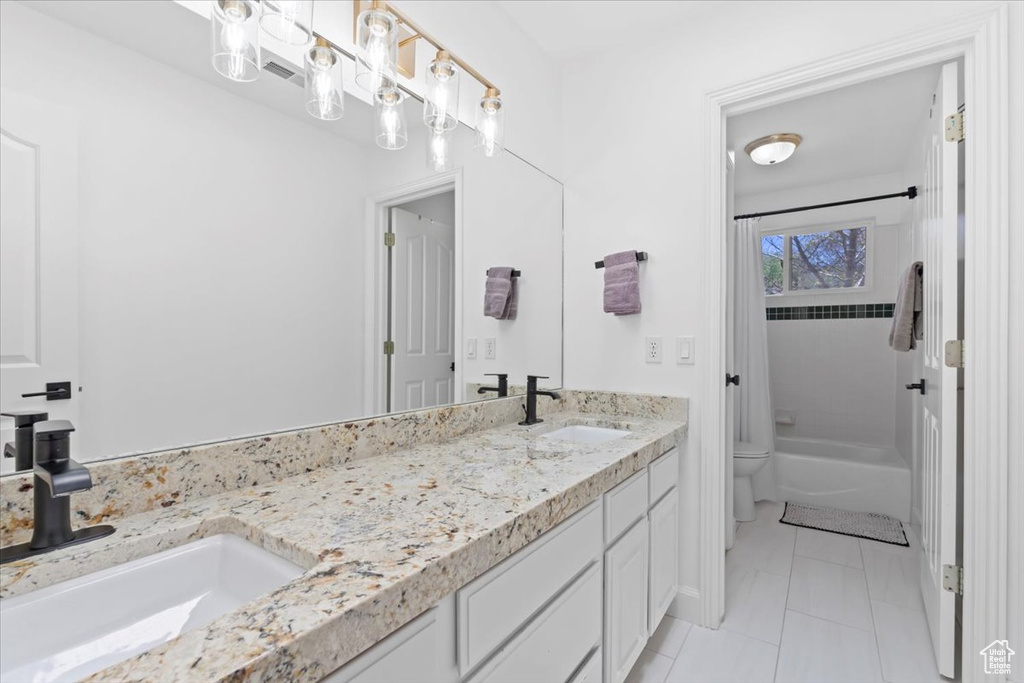 Full bath with toilet, double vanity, shower / bath combination with curtain, and tile patterned floors