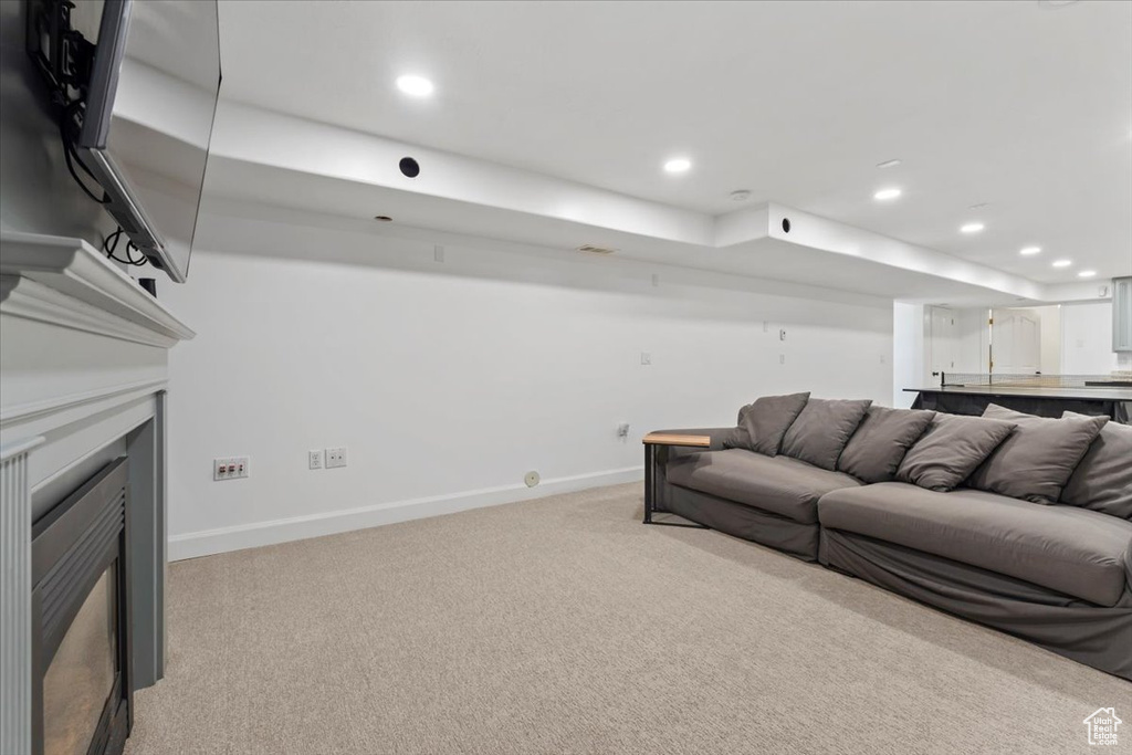 Living area with light colored carpet, baseboards, recessed lighting, and a fireplace