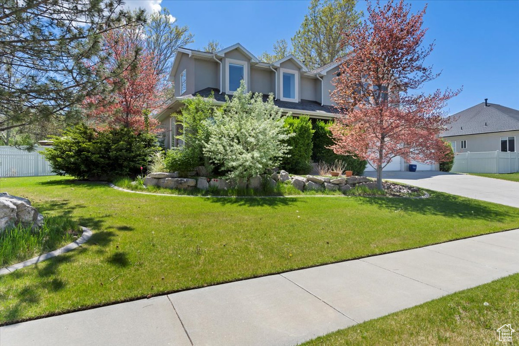 View of property hidden behind natural elements featuring concrete driveway and stucco siding