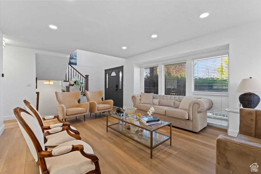 Living room featuring light wood-style flooring, stairs, recessed lighting, and baseboards
