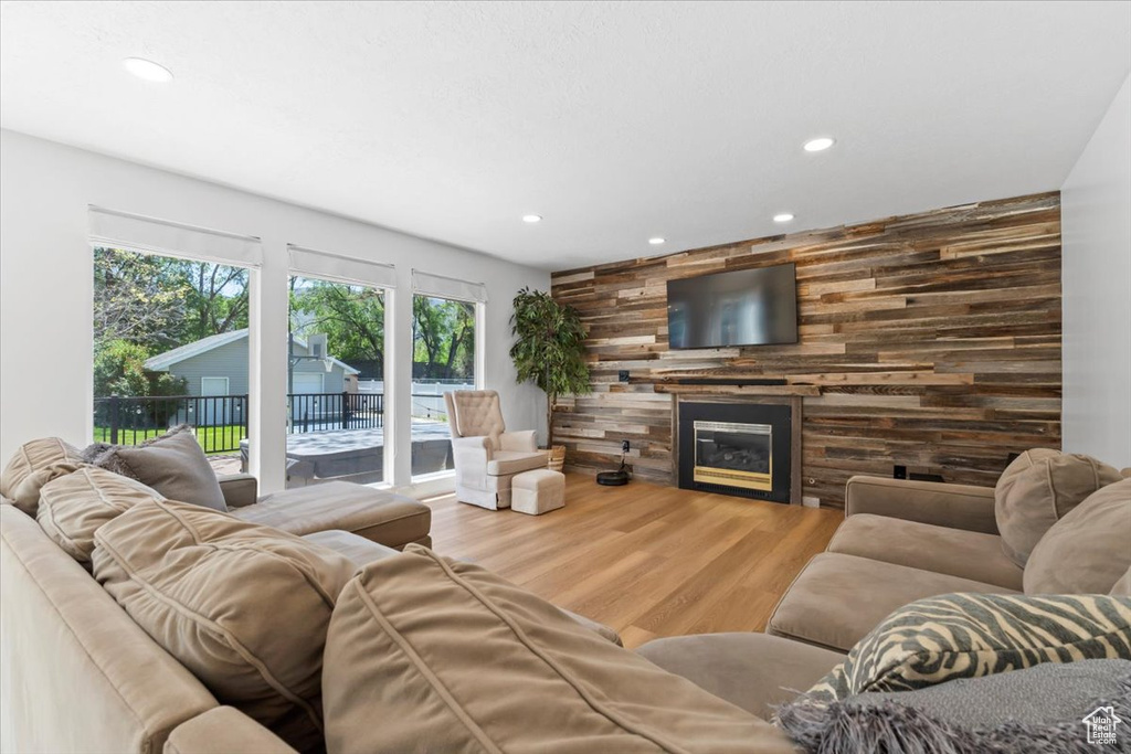 Living room featuring recessed lighting, a large fireplace, wood finished floors, wood walls, and an accent wall