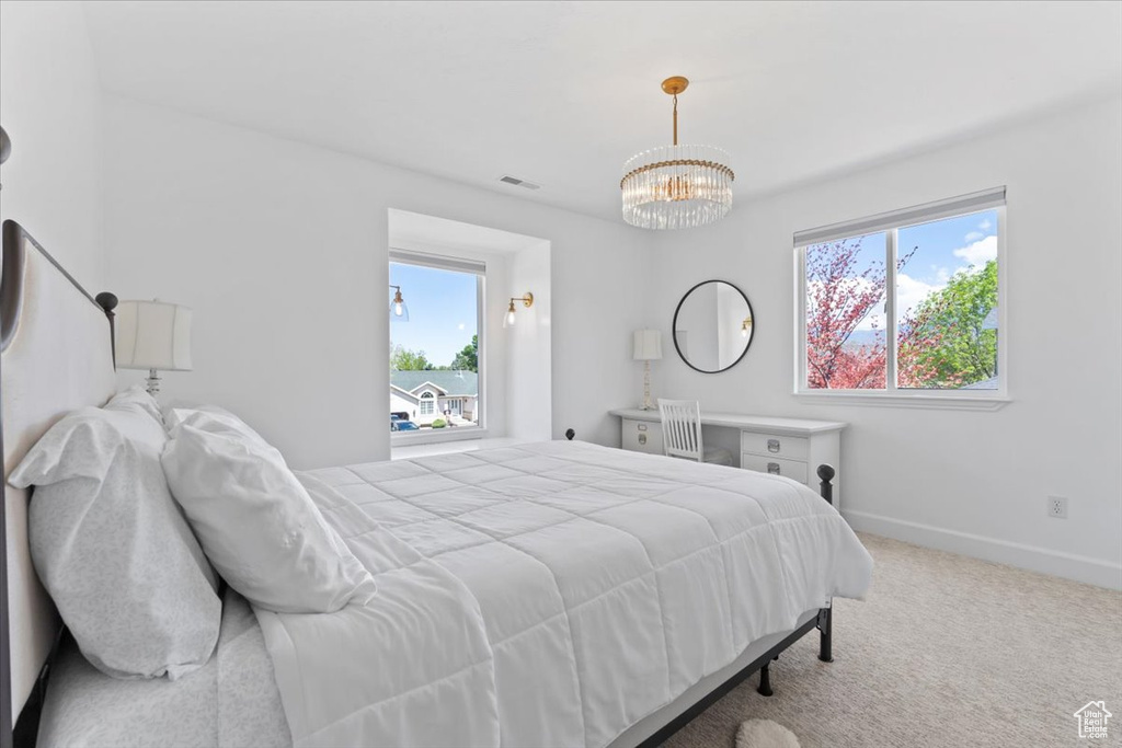 Carpeted bedroom with a chandelier and baseboards