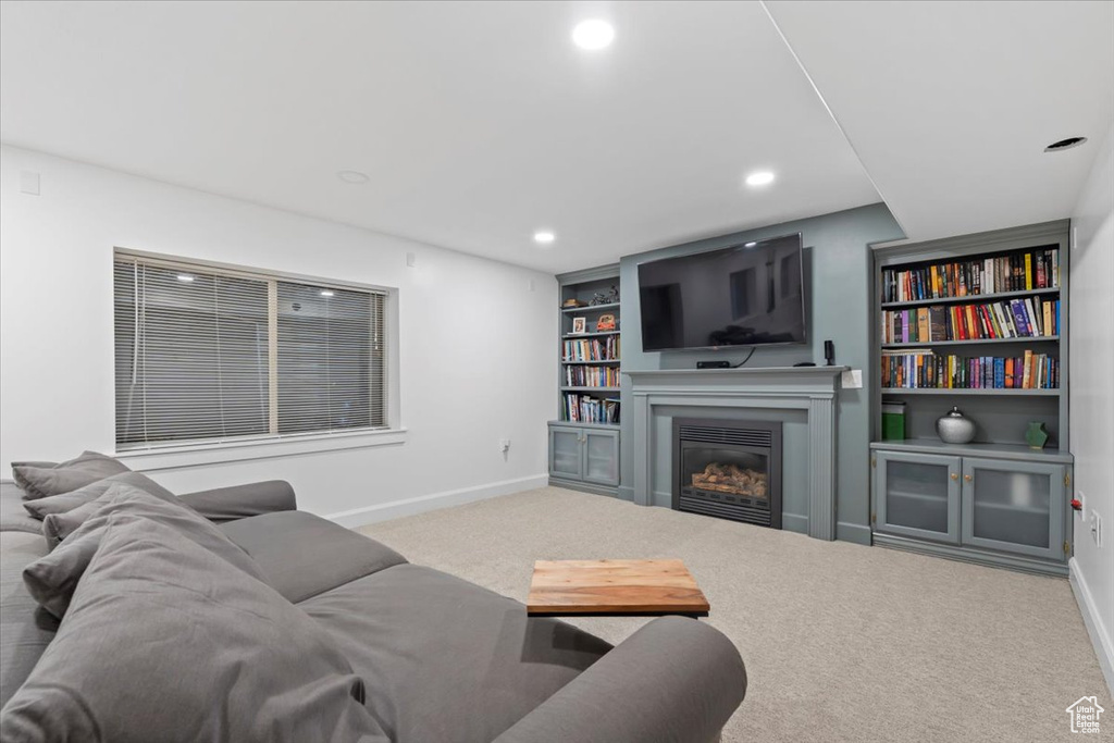 Living room with baseboards, recessed lighting, carpet flooring, a glass covered fireplace, and built in features
