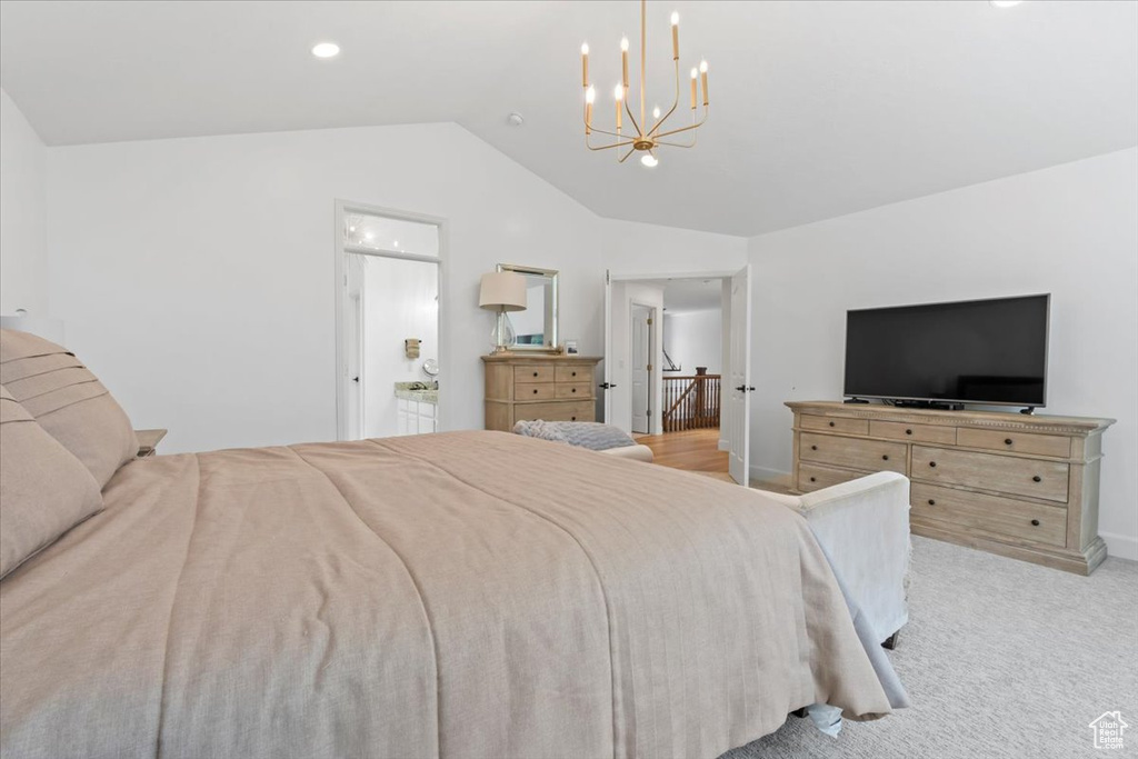 Bedroom featuring vaulted ceiling, a chandelier, light carpet, baseboards, and connected bathroom