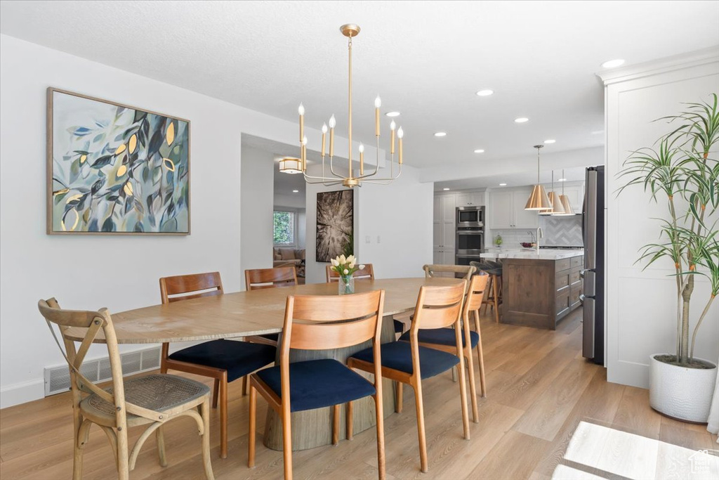 Dining area featuring light wood-style floors, recessed lighting, and a chandelier