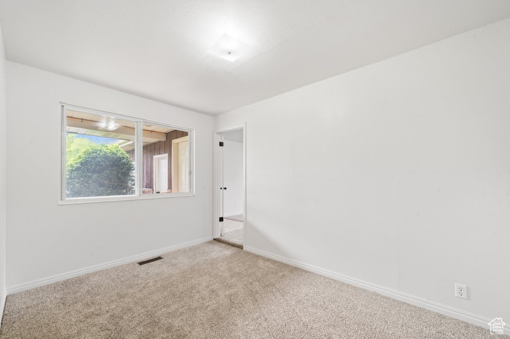 Carpeted spare room featuring baseboards