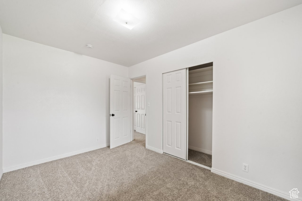 Unfurnished bedroom featuring carpet, baseboards, and a closet