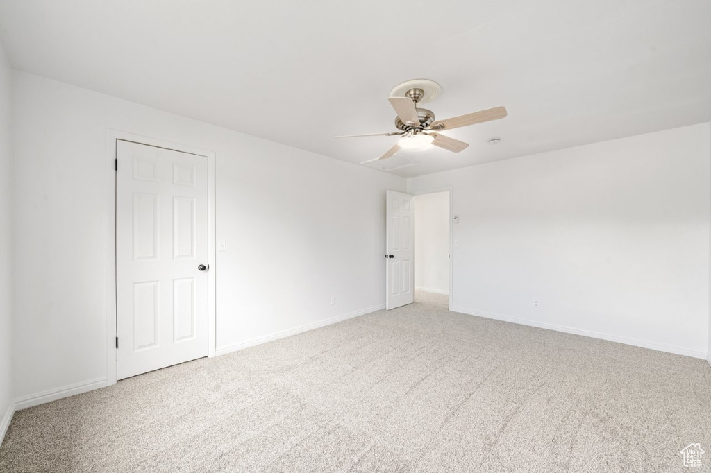Empty room with light carpet, a ceiling fan, and baseboards