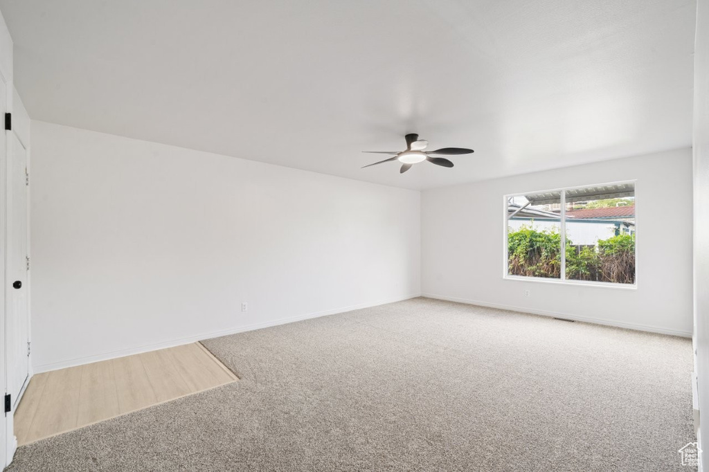 Carpeted empty room with ceiling fan and baseboards