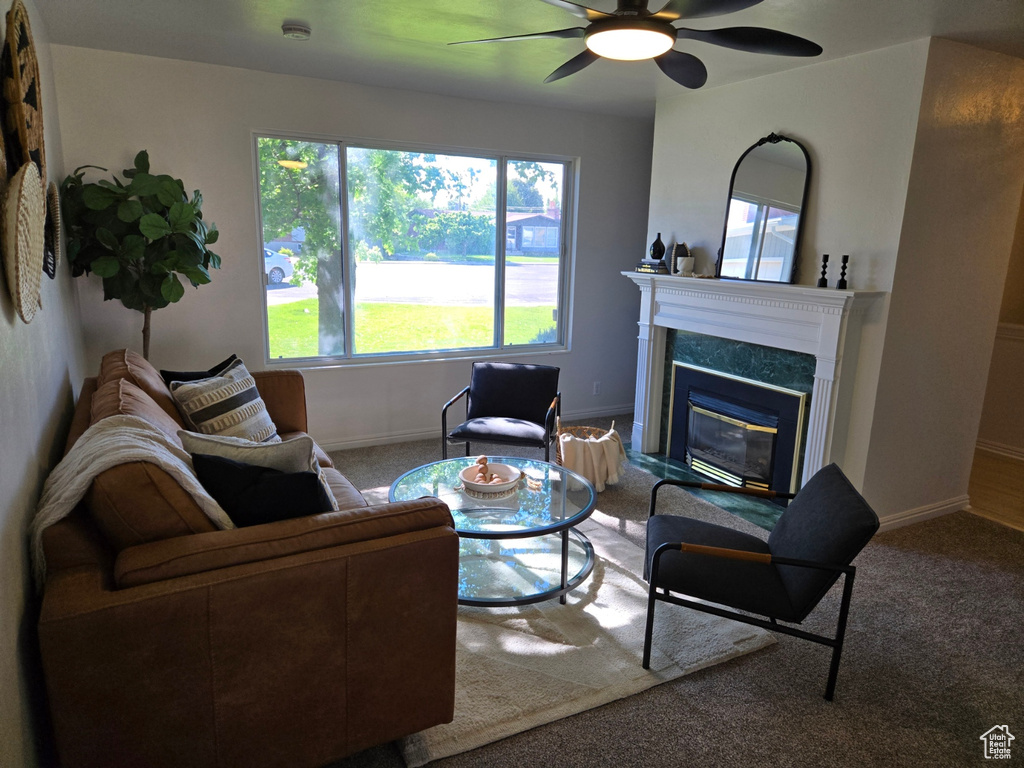 Living area with carpet floors, baseboards, a ceiling fan, and a high end fireplace