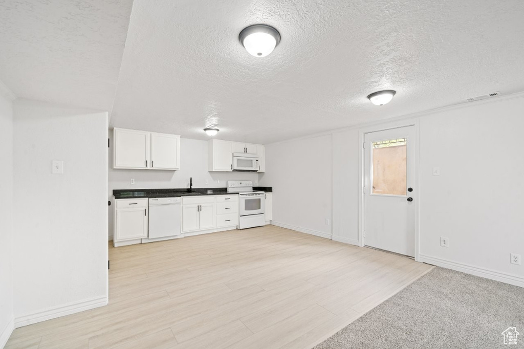 Kitchen featuring white appliances, a textured ceiling, baseboards, and dark countertops