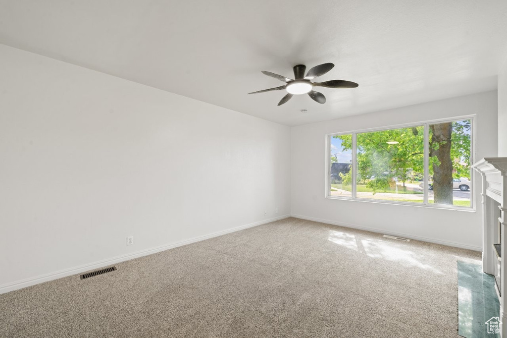 Carpeted spare room with a ceiling fan and baseboards