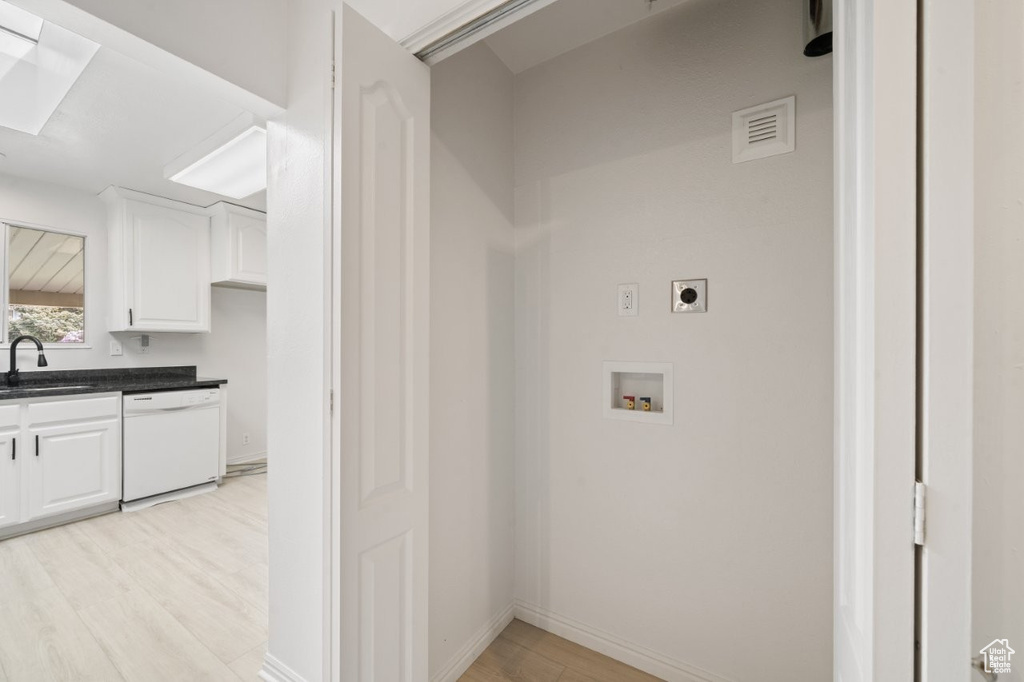 Laundry area with electric dryer hookup, light wood-style floors, hookup for a washing machine, and baseboards