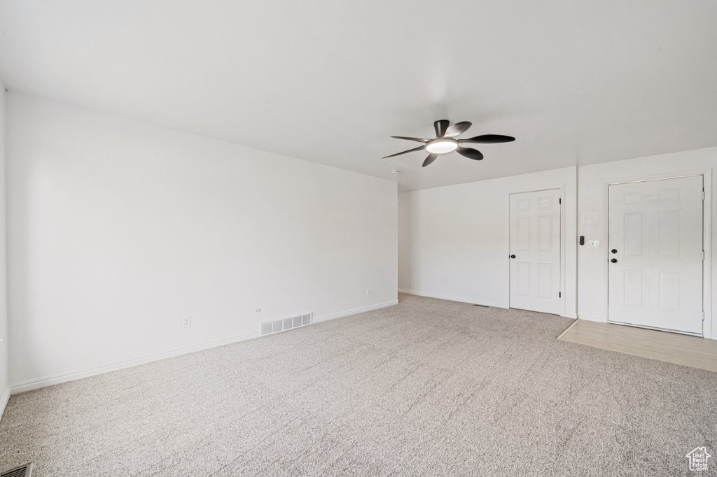 Spare room featuring light carpet, ceiling fan, and baseboards