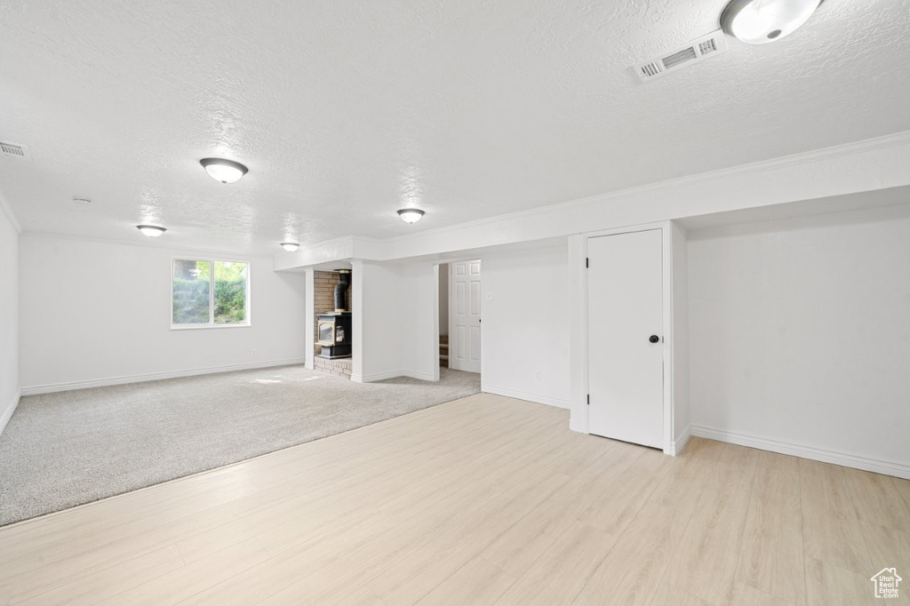 Basement with a textured ceiling, light wood-type flooring, and baseboards