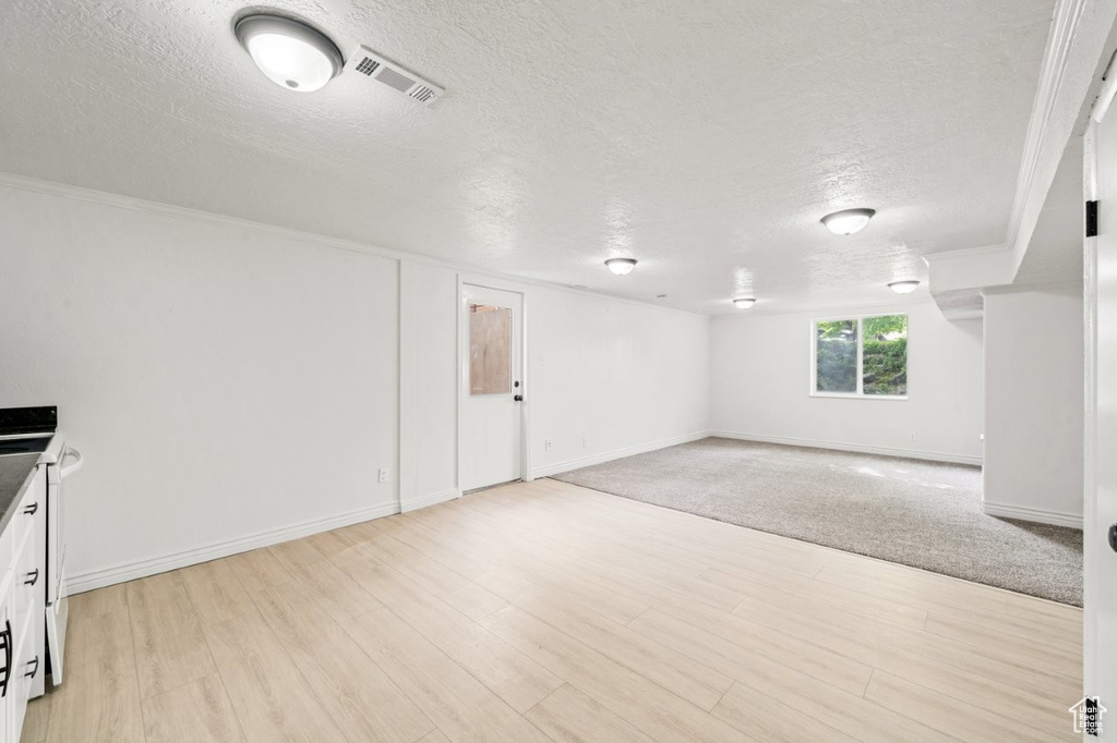 Below grade area featuring a textured ceiling, light wood finished floors, and baseboards