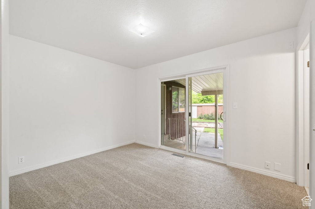 Carpeted spare room featuring baseboards