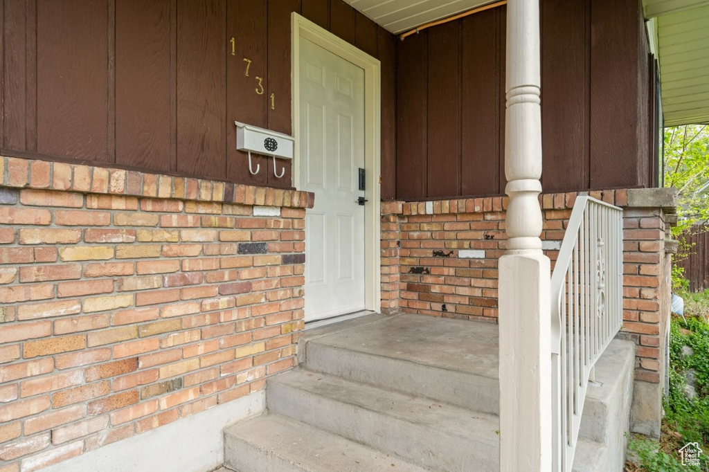 View of exterior entry featuring brick siding and a porch