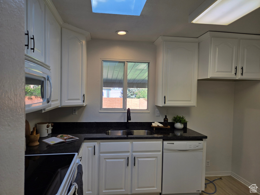 Kitchen featuring white appliances, a sink, white cabinetry, and recessed lighting