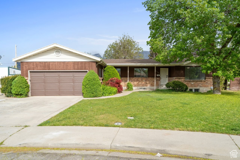 Ranch-style house with a garage, a front yard, concrete driveway, covered porch, and brick siding