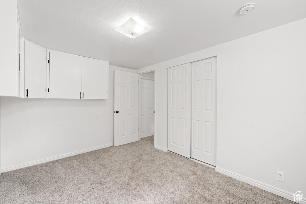 Unfurnished bedroom with light colored carpet, baseboards, and a closet