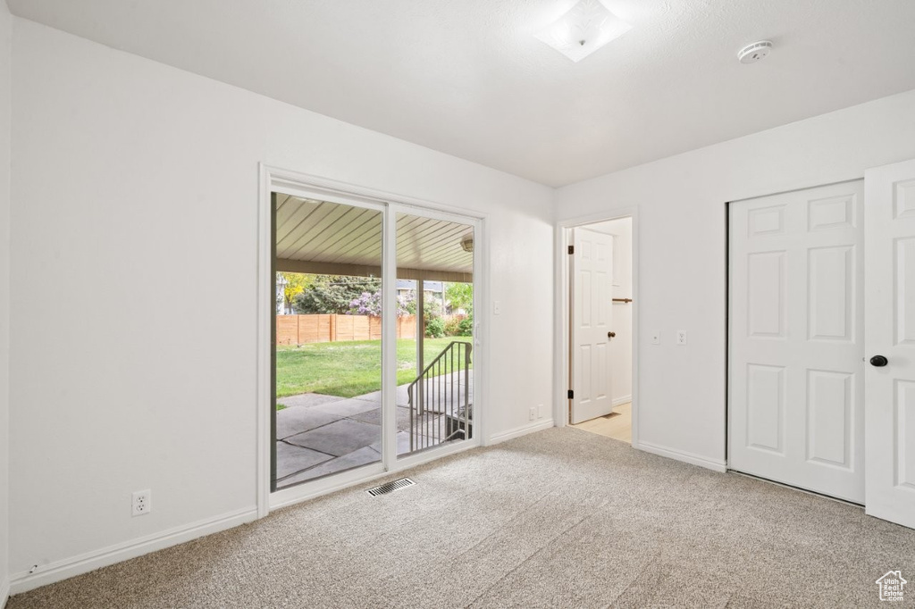 Unfurnished bedroom featuring access to outside, carpet floors, and baseboards