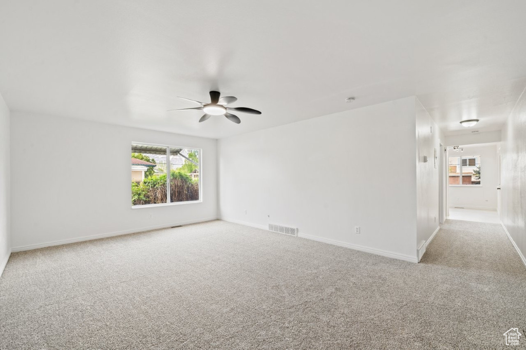 Carpeted spare room with ceiling fan and baseboards